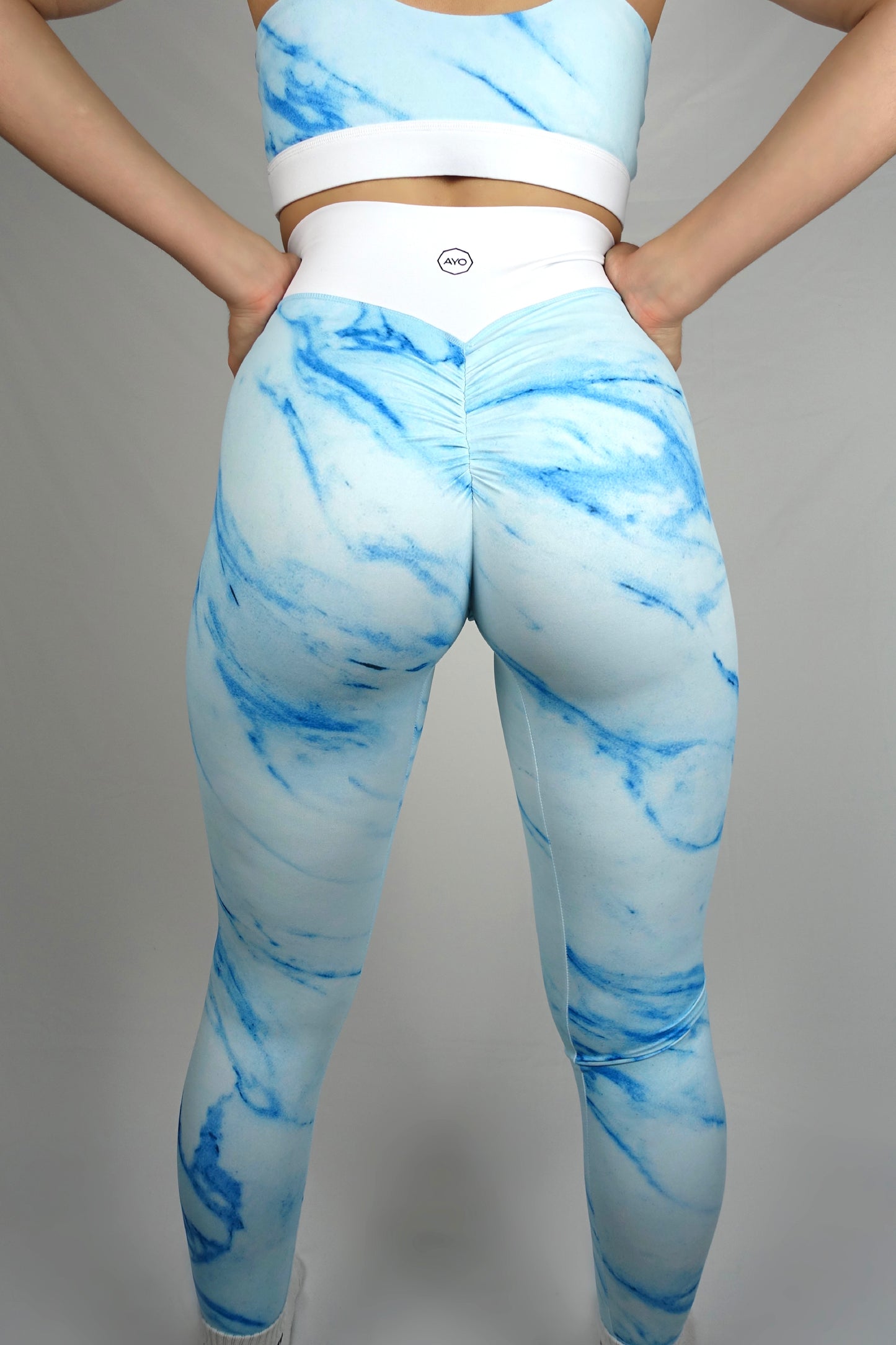 Scrunch butt women activewear leggings with a white waistband and bright turquoise legs back angle